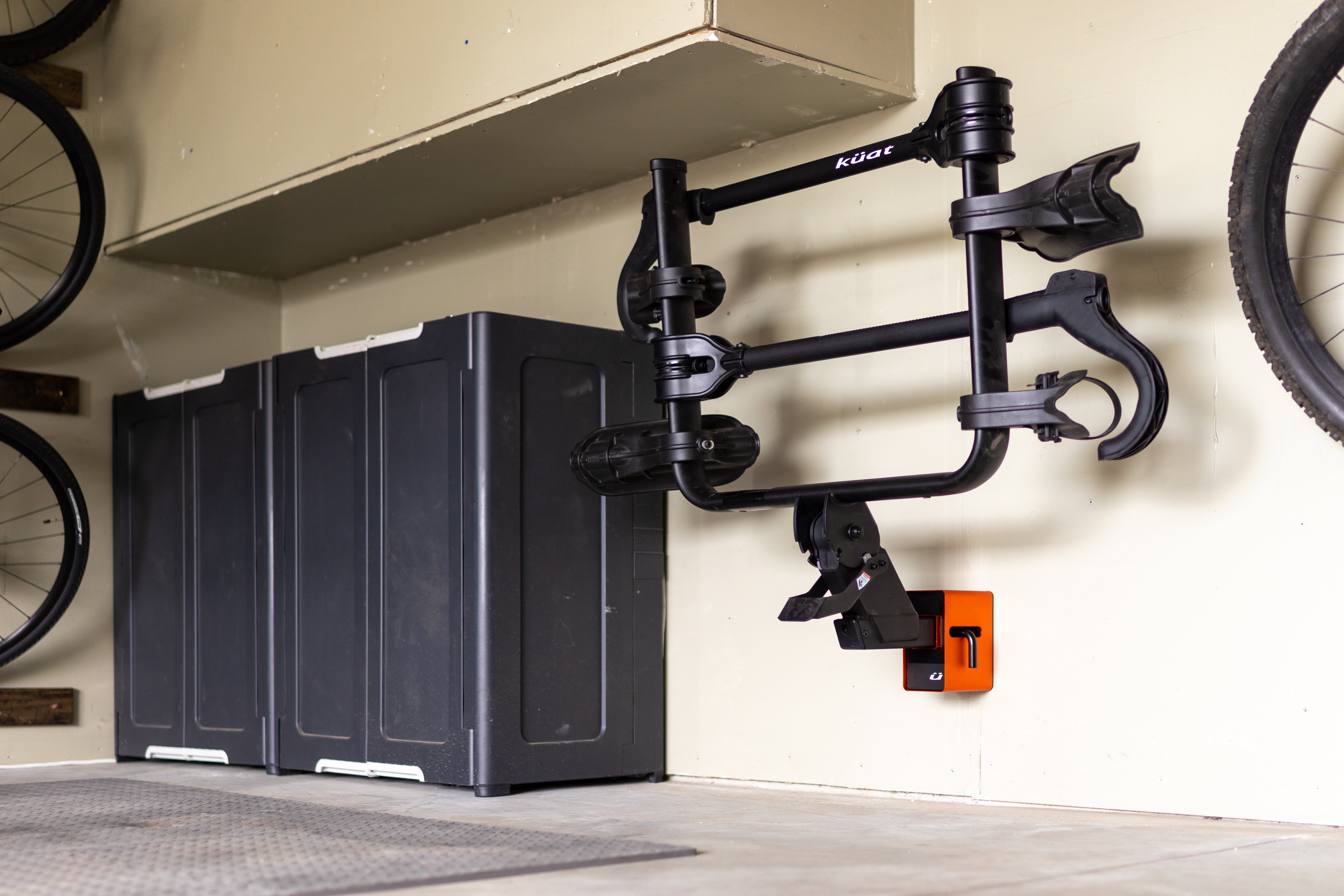 Bicycle storage solution with black bike stand and storage boxes in a garage setting.