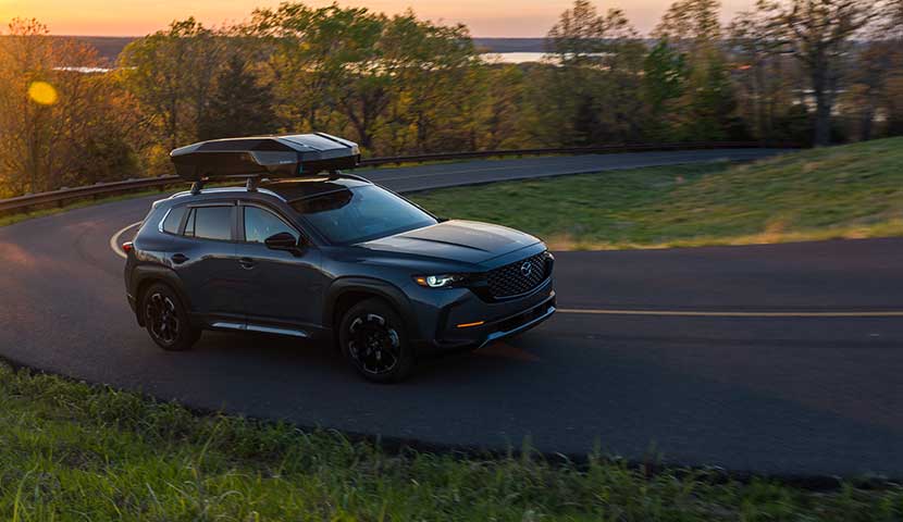 SUV with a roof cargo box rack on a road during sunset